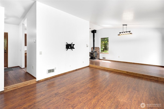 23611 Friar Creek Rd, Monroe, WA 98272 - empty room featuring a wood stove, vaulted ceiling, and dark wood-style floors