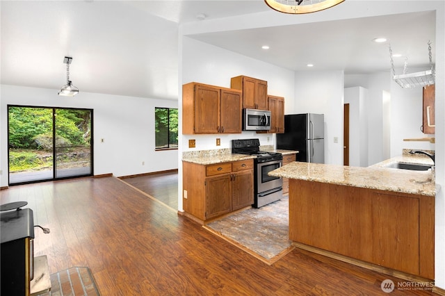23611 Friar Creek Rd, Monroe, WA 98272 - kitchen with stainless steel appliances, brown cabinetry, a peninsula, light stone counters, and wood finished floors