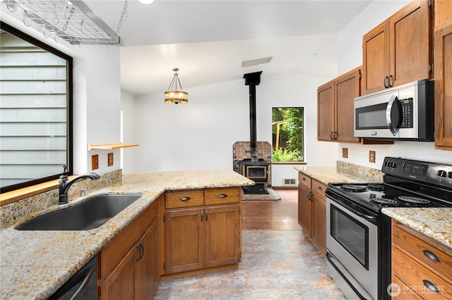 23611 Friar Creek Rd, Monroe, WA 98272 - kitchen with appliances with stainless steel finishes, a wood stove, brown cabinets, and light stone counters
