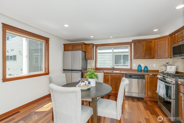12046 33rd Ave NE Unit A, Seattle, WA 98125 - kitchen with stainless steel appliances, a sink, wood finished floors, tasteful backsplash, and brown cabinetry
