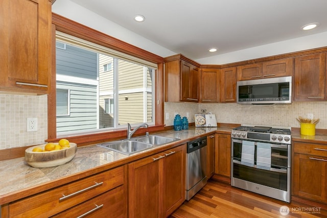 12046 33rd Ave NE Unit A, Seattle, WA 98125 - kitchen with appliances with stainless steel finishes, a sink, brown cabinets, wood finished floors, and tasteful backsplash