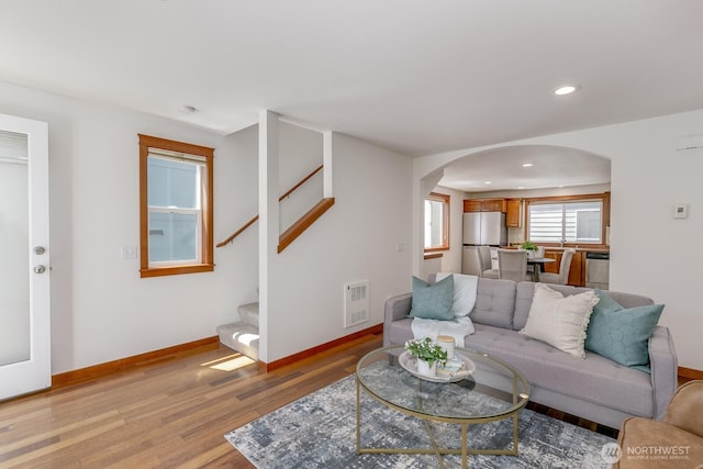 12046 33rd Ave NE Unit A, Seattle, WA 98125 - living area with arched walkways, light wood finished floors, stairs, heating unit, and baseboards