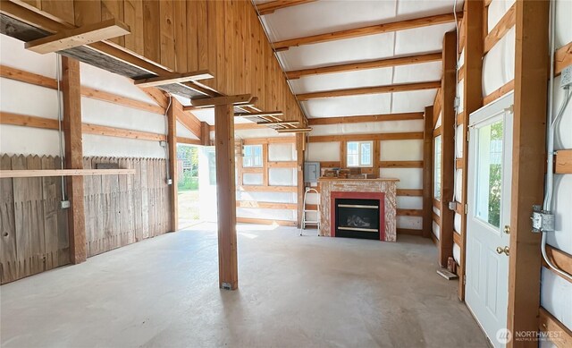 7459 Blaine Rd, Blaine, WA 98230 - unfurnished living room featuring concrete floors, healthy amount of natural light, wooden walls, and a fireplace