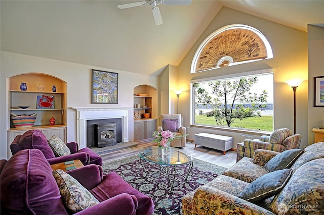 478 Eagle Crest Rd, Camano Island, WA 98282 - living room with high vaulted ceiling, built in shelves, wood finished floors, a fireplace with raised hearth, and a ceiling fan