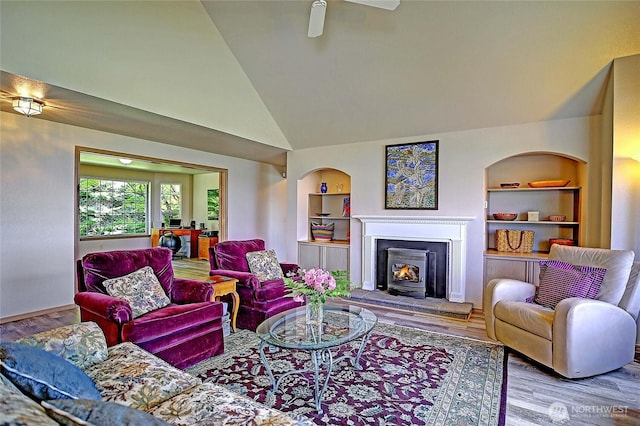 478 Eagle Crest Rd, Camano Island, WA 98282 - living area featuring built in features, wood finished floors, a warm lit fireplace, ceiling fan, and high vaulted ceiling