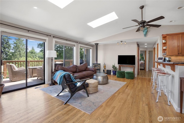 2715 Garfield Ave SE, Port Orchard, WA 98366 - living room featuring a skylight, lofted ceiling, a wood stove, light wood-style floors, and a ceiling fan