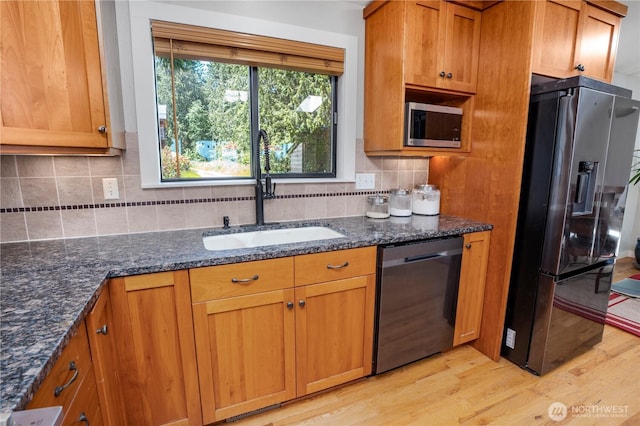 2715 Garfield Ave SE, Port Orchard, WA 98366 - kitchen featuring appliances with stainless steel finishes, a sink, light wood-type flooring, dark stone countertops, and backsplash