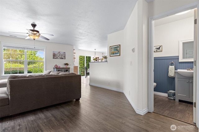 12524 SE 295th St, Auburn, WA 98092 - living area with ceiling fan, dark wood-style flooring, baseboards, and a wainscoted wall