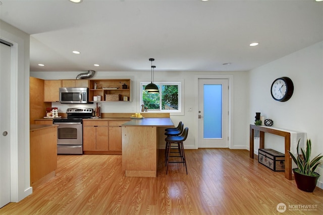 9030 6th Ave NW, Seattle, WA 98117 - kitchen with stainless steel appliances, open shelves, a kitchen breakfast bar, light wood-style floors, and recessed lighting