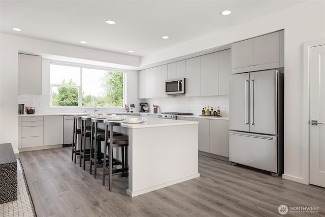 3915 198th St SE Unit B2, Bothell, WA 98012 - kitchen with appliances with stainless steel finishes, decorative backsplash, a center island, light countertops, and light wood-style flooring