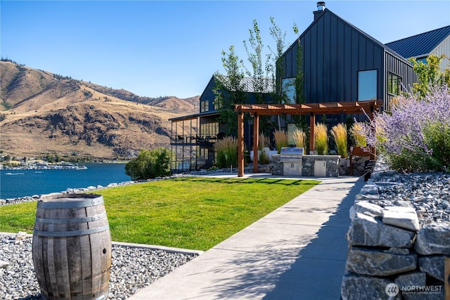203 Bluebell Ct, Chelan, WA 98816 - view of green lawn with exterior kitchen, a pergola, a water and mountain view, and a patio