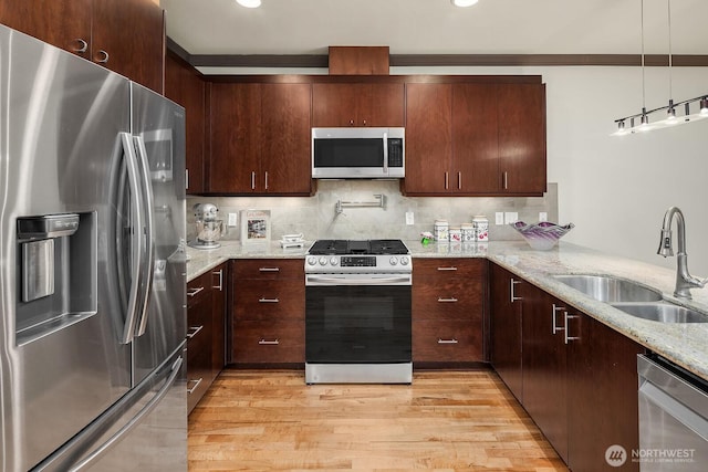 18609 SE Newport Way Unit 408, Issaquah, WA 98027 - kitchen with stainless steel appliances, a sink, light wood finished floors, light stone counters, and decorative backsplash