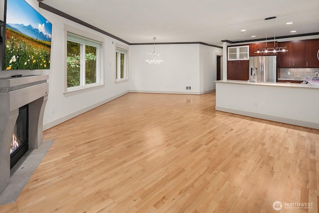 18609 SE Newport Way Unit 408, Issaquah, WA 98027 - unfurnished living room with a chandelier, a premium fireplace, baseboards, light wood-style flooring, and ornamental molding