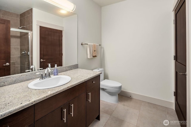 18609 SE Newport Way Unit 408, Issaquah, WA 98027 - bathroom featuring vanity, toilet, a tile shower, baseboards, and tile patterned floors