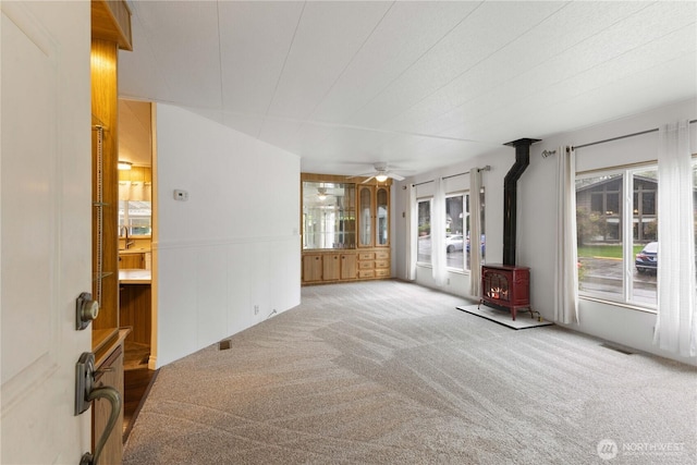11216 127th St E Unit 19, Puyallup, WA 98374 - unfurnished living room featuring a wood stove, carpet, and a ceiling fan