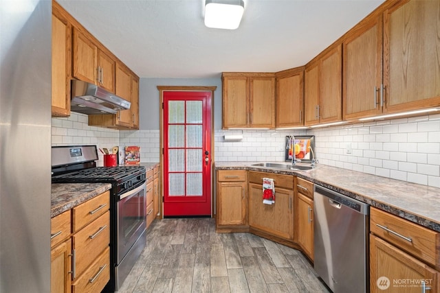 2526 19th St, Bremerton, WA 98312 - kitchen featuring under cabinet range hood, stainless steel appliances, wood finished floors, a sink, and brown cabinetry