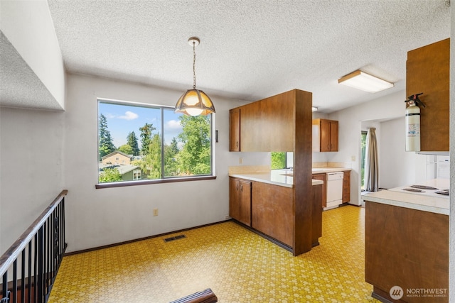 1015 143rd St S, Tacoma, WA 98444 - kitchen with brown cabinets, dishwasher, light countertops, light flooring, and pendant lighting