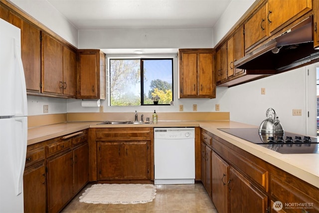 1119 Sunset Ave, Bellingham, WA 98226 - kitchen featuring white appliances, a sink, under cabinet range hood, light countertops, and brown cabinetry