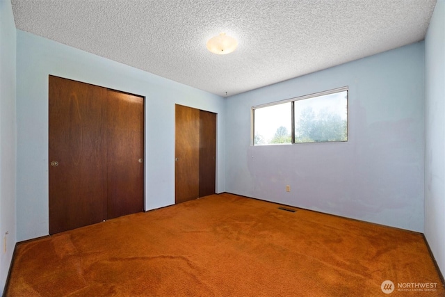 1119 Sunset Ave, Bellingham, WA 98226 - unfurnished bedroom featuring two closets, carpet, and a textured ceiling