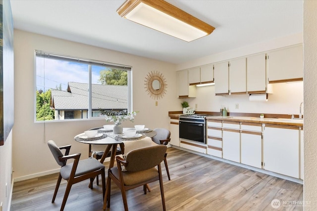 8225 212th St SW # 302, Edmonds, WA 98026 - kitchen featuring range with electric stovetop, light wood-style flooring, light countertops, a sink, and white cabinetry