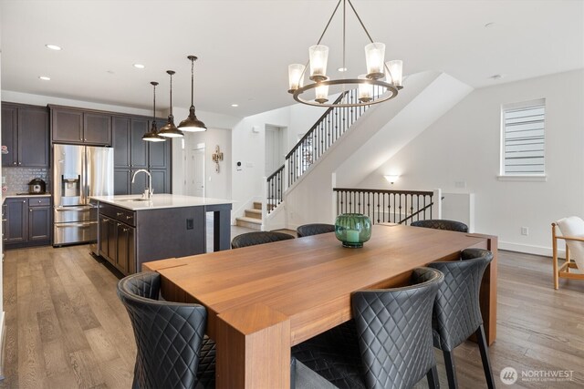 26627 NE Boyd Way Unit 101, Duvall, WA 98019 - dining room featuring light wood finished floors, a chandelier, recessed lighting, baseboards, and stairs