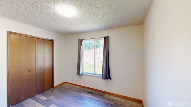504 Ash St N, Omak, WA 98841 - unfurnished bedroom featuring wood finished floors, a closet, a textured ceiling, and baseboards