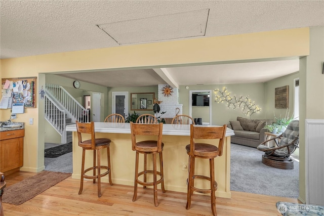 3256 S 360th St, Auburn, WA 98001 - kitchen featuring a kitchen breakfast bar, light wood finished floors, open floor plan, brown cabinets, and beamed ceiling