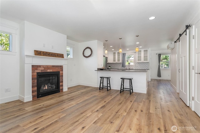 2730-2734 Nevada St, Bellingham, WA 98226 - kitchen with a peninsula, white cabinets, glass insert cabinets, a barn door, and light wood-type flooring