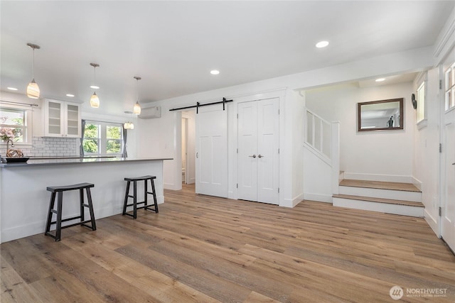 2730-2734 Nevada St, Bellingham, WA 98226 - kitchen featuring a barn door, white cabinets, a breakfast bar area, recessed lighting, and light wood-style flooring