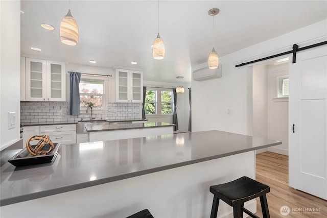2730-2734 Nevada St, Bellingham, WA 98226 - kitchen featuring a sink, dark countertops, a barn door, a breakfast bar area, and white cabinets