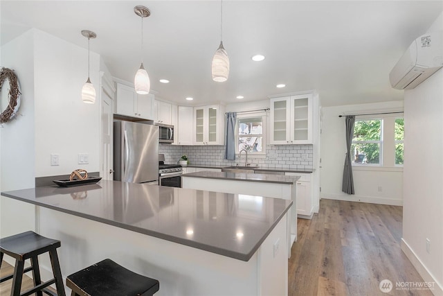 2730-2734 Nevada St, Bellingham, WA 98226 - kitchen with appliances with stainless steel finishes, a peninsula, a wall mounted AC, a sink, and light wood finished floors