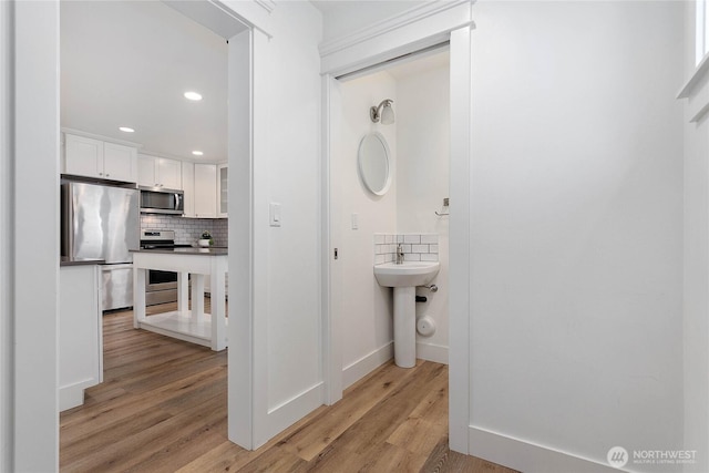 2730-2734 Nevada St, Bellingham, WA 98226 - bathroom featuring wood finished floors, decorative backsplash, recessed lighting, a sink, and baseboards