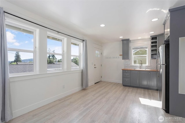2730-2734 Nevada St, Bellingham, WA 98226 - kitchen with gray cabinetry, freestanding refrigerator, baseboards, light wood-type flooring, and decorative backsplash