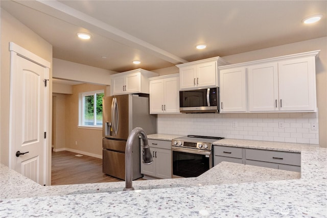 31823 44th Ave S, Auburn, WA 98001 - kitchen with stainless steel appliances, wood finished floors, decorative backsplash, light stone counters, and white cabinets