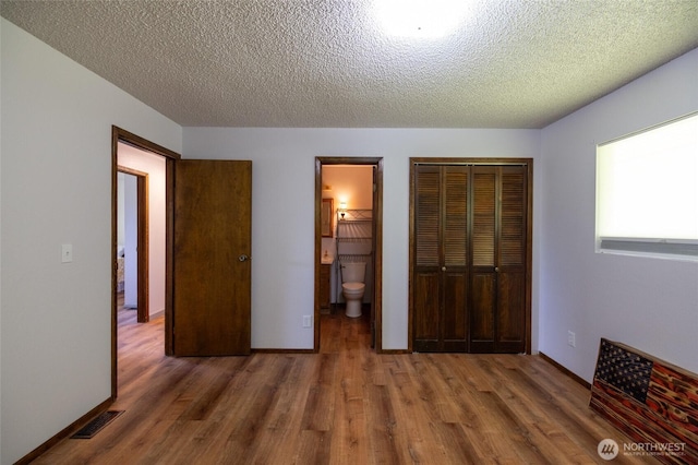 371 Pigeon Springs Rd, Onalaska, WA 98570 - unfurnished bedroom featuring wood finished floors, a textured ceiling, a closet, and connected bathroom