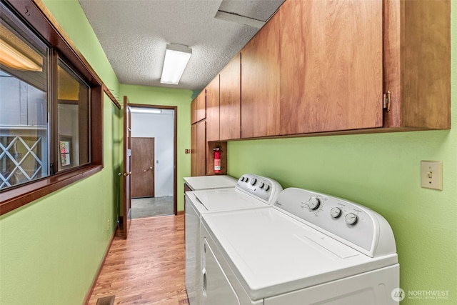 1086 W State Route 4, Skamokawa, WA 98647 - washroom with cabinet space, washer and clothes dryer, a textured ceiling, and light wood-style floors