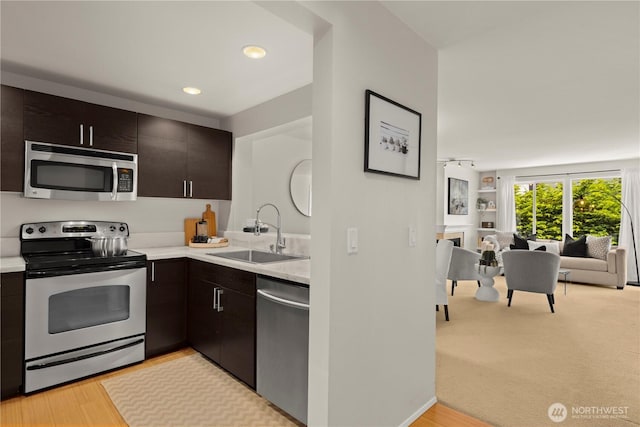 1400 Taylor Ave N Unit 203, Seattle, WA 98109 - kitchen featuring stainless steel appliances, a sink, open floor plan, light countertops, and dark brown cabinets