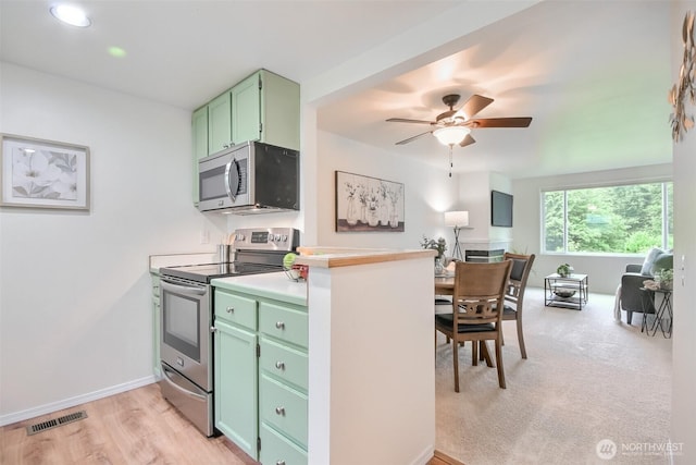 22002 SE 40th Ln Unit 1111, Issaquah, WA 98029 - kitchen featuring appliances with stainless steel finishes, green cabinets, ceiling fan, light countertops, and light wood-style floors