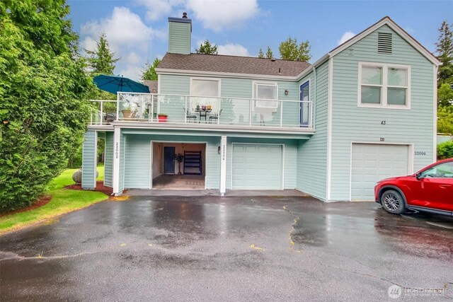 22002 SE 40th Ln Unit 1111, Issaquah, WA 98029 - view of front of house featuring a balcony, a garage, a chimney, and driveway