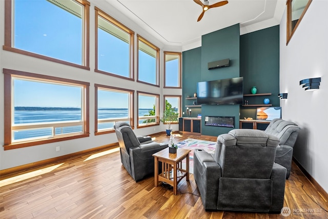 8210 Walnut Rd NE, Olympia, WA 98516 - living room with a towering ceiling, wood finished floors, a ceiling fan, baseboards, and a glass covered fireplace