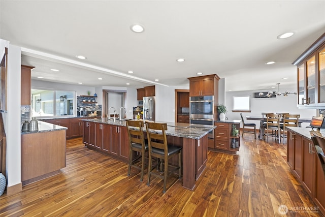 8210 Walnut Rd NE, Olympia, WA 98516 - kitchen with stainless steel appliances, an island with sink, dark wood finished floors, recessed lighting, and dark stone countertops