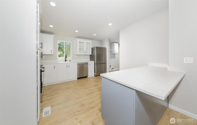 20215 Crystal Springs Dr, Granite Falls, WA 98252 - kitchen with stainless steel appliances, a peninsula, a sink, light wood finished floors, and white cabinets