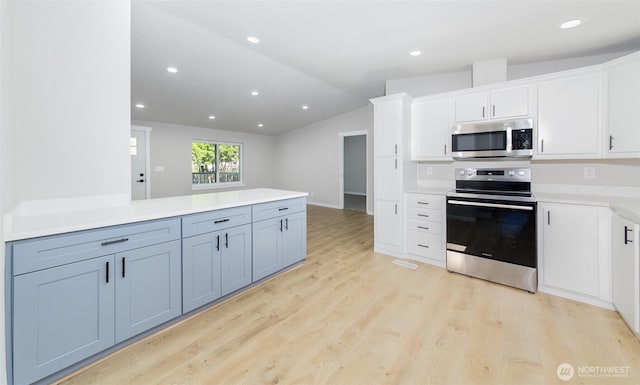 20215 Crystal Springs Dr, Granite Falls, WA 98252 - kitchen featuring stainless steel appliances, lofted ceiling, light wood finished floors, light countertops, and white cabinetry