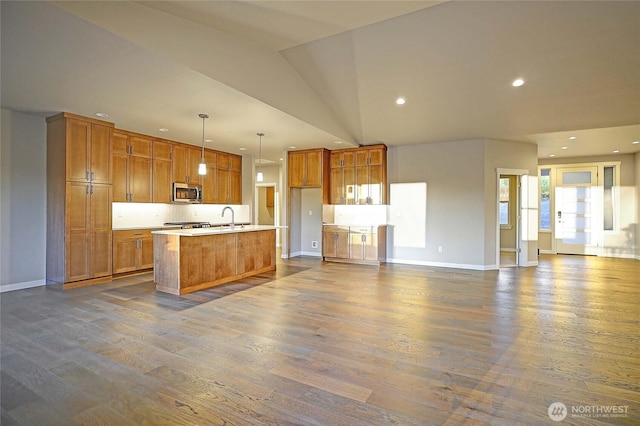 161 N Camano Ridge Rd, Camano Island, WA 98282 - kitchen featuring stainless steel microwave, a sink, brown cabinetry, dark wood-style floors, and open floor plan