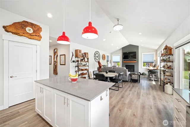 7420 Windsong Ln, Sedro Woolley, WA 98284 - kitchen featuring vaulted ceiling, light wood-type flooring, a kitchen island, white cabinetry, and a large fireplace