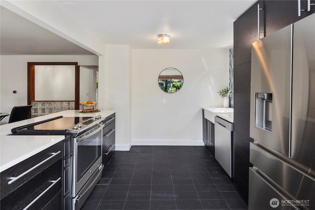 8414 9th Ave SW, Seattle, WA 98106 - kitchen with stainless steel appliances, light countertops, dark tile patterned floors, dark cabinets, and modern cabinets