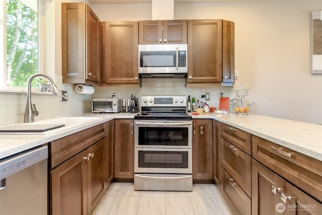 2311 Milton Way Unit F, Milton, WA 98354 - kitchen with appliances with stainless steel finishes, a sink, tasteful backsplash, light tile patterned floors, and brown cabinetry