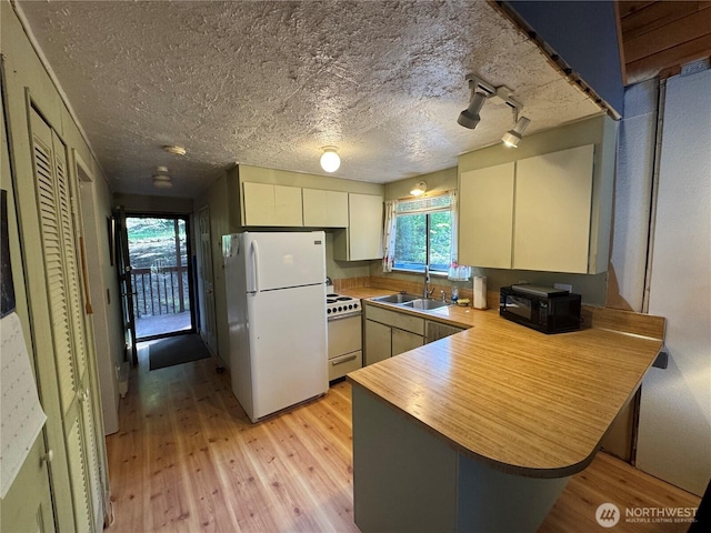 22337 Bluewater Dr SE, Yelm, WA 98597 - kitchen with white appliances, a peninsula, a sink, light wood-style floors, and healthy amount of natural light