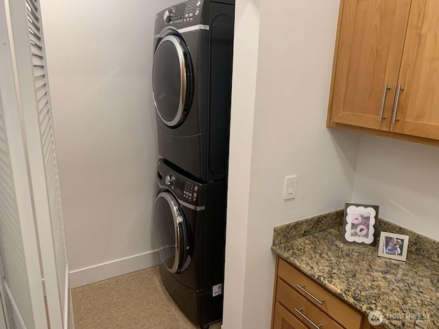 375 Kirkland Ave Unit 145, Kirkland, WA 98033 - washroom featuring stacked washer and clothes dryer, cabinet space, and baseboards