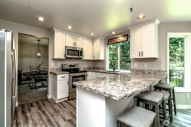 11608 SE 228th Pl, Kent, WA 98031 - kitchen with stainless steel appliances, wood finished floors, a peninsula, white cabinets, and a sink